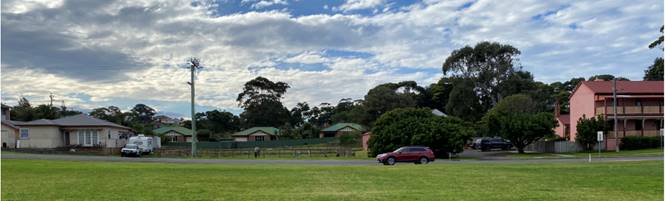 A grassy field with trees and buildings in the background

Description automatically generated with low confidence