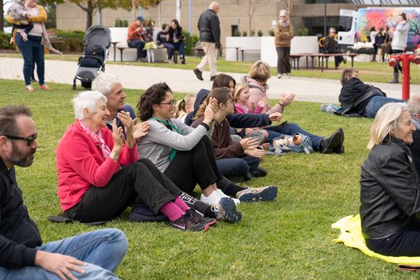 A group of people sitting on the grass

Description automatically generated