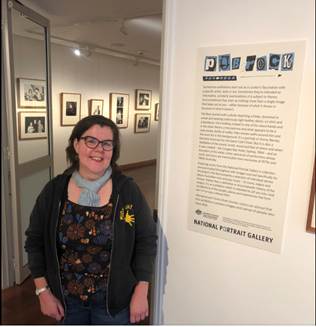 A person standing next to a poster

Description automatically generated