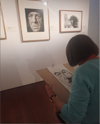 A person drawing on a piece of paper

Description automatically generated